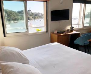 a bedroom with a bed and a view of a beach at Hôtel Beau Soleil in Pornic