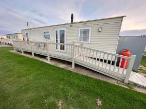 a mobile home with a porch and a white fence at Disabled 4 Berth in Ingoldmells