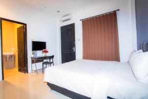 Livinn Hotel Kendangsari Surabaya في سورابايا: غرفة نوم بسرير ومكتب وتلفزيون