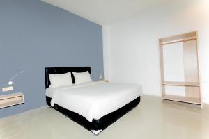 Livinn Hotel Kendangsari Surabaya في سورابايا: سرير أبيض في غرفة بيضاء مع نافذة