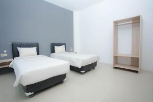 Habitación con 2 camas y espejo. en Livinn Hotel Kendangsari Surabaya en Surabaya