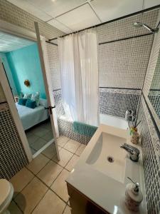 uma casa de banho com um lavatório, um chuveiro e uma banheira em La Puerta Azul em Jávea