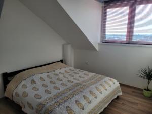 a bedroom with a bed and two windows at LUCA tetőtéri Apartman in Pápa