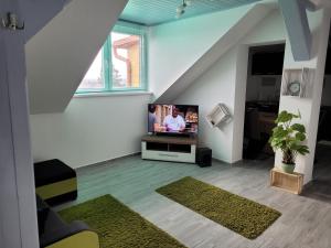 sala de estar con TV en medio de una escalera en LUCA tetőtéri Apartman, en Pápa