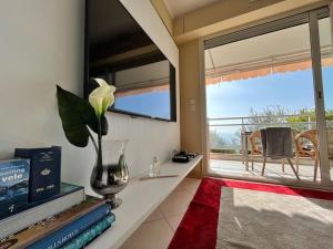 un salon avec une fenêtre et un vase avec une fleur dans l'établissement Les Jardins de Monaco vue mer et piscine, à Saint-Antoine