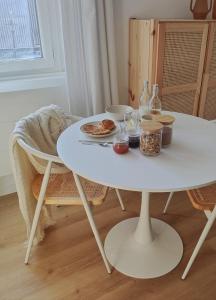 einen weißen Tisch mit einem Teller Essen drauf. in der Unterkunft Le Studio in Saint-Gilles