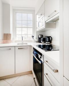 a kitchen with white cabinets and a stove top oven at Hyde Park Apartments in London