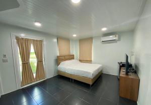 a bedroom with a bed and a television and a window at WHITE Houseรีสอร์ท in Ban Bung Thap Tae (1)