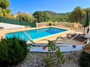 a swimming pool in a yard with a table and an umbrella at La Puerta Azul in Jávea