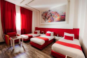 a room with three beds and red curtains at WINDSOR HOTEL CITY CENTER in Casablanca