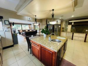 a kitchen and living room with a sink and a counter at Palms On Byrne: Where Elegance Meets Serenity in Durban