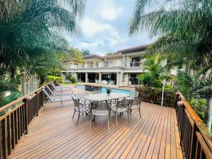 a wooden deck with a table and chairs on a house at Palms On Byrne: Where Elegance Meets Serenity in Durban