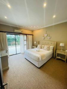a bedroom with a white bed and a large window at Palms On Byrne: Where Elegance Meets Serenity in Durban +47 photos