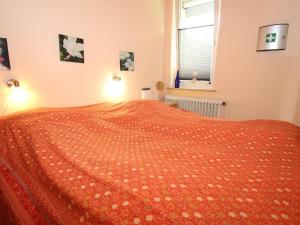 ein Schlafzimmer mit einem Bett mit einer orangefarbenen Tagesdecke in der Unterkunft Bungalow, Berumburg in Berumbur