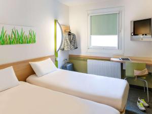 una camera d'albergo con due letti e una finestra di ibis budget Strasbourg Sud Illkirch a Geispolsheim