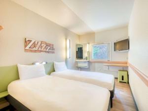 a hotel room with two beds and a tv at ibis budget Versailles - Trappes in Trappes