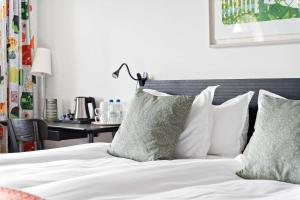 een bed met witte lakens en kussens naast een bureau bij Landvetter Airport Hotel, Best Western Premier Collection in Landvetter