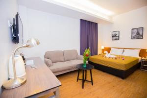 a hotel room with a bed and a couch at Urban Inn Kulim in Kulim