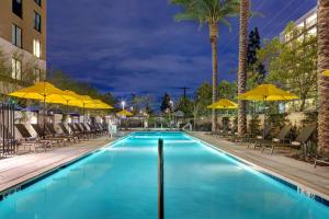 a swimming pool with chairs and umbrellas at night at Hilton Garden Inn Anaheim Resort in Anaheim