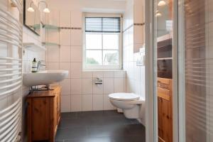 a bathroom with a toilet and a sink and a window at LH Heidegrund, App 3 in Wenningstedt +8 photos
