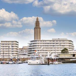 una barca è ormeggiata di fronte a un grande edificio di Hilton Garden Inn Le Havre Centre a Le Havre