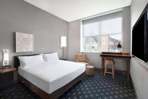 丹佛The Slate Hotel Denver Downtown, Tapestry by Hilton的一间卧室，配有一张床、一张书桌和一台电视
