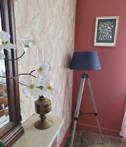 une lampe et un trépied à côté d'un mur fleuri dans l'établissement Gîte Moussette - Bord de Mer - 4/6 pers., à Quinéville