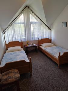 two beds in a room with a table and windows at Prenoćište San Rooms in Livno