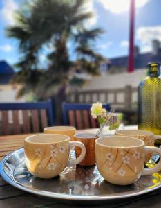 taca z trzema filiżankami kawy na stole w obiekcie Gîte Moussette - Bord de Mer - 4/6 pers. w mieście Quinéville