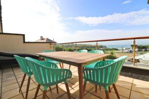 a wooden table and chairs on a balcony at Beachside apartment, sea views in Saint Merryn