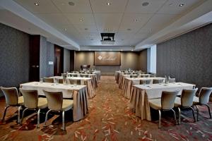 Colcord Hotel Oklahoma City, Curio Collection by Hilton في مدينة اوكلاهوما: قاعة اجتماعات بطاولات بيضاء وكراسي وشاشة