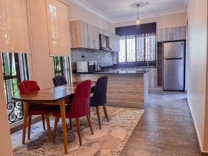 a kitchen with a wooden table and red chairs at Bellwether Apartments in Kampala
