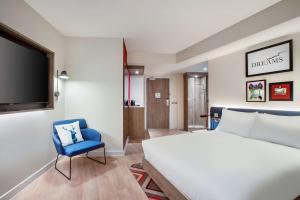 a bedroom with a white bed and a blue chair at Hampton By Hilton Bath City in Bath