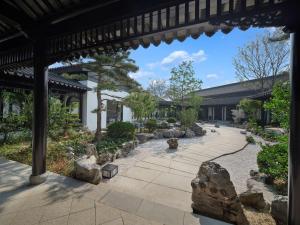 a garden with rocks and trees and a building at Doubletree By Hilton Yancheng Dayangwan in Yancheng