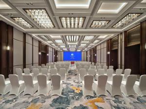 una sala de conferencias con sillas blancas y pantalla azul en Doubletree By Hilton Yancheng Dayangwan, en Yancheng
