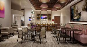 um restaurante com mesas e cadeiras e um bar em The Banyan Hotel Fort Myers, Tapestry Collection by Hilton em Fort Myers