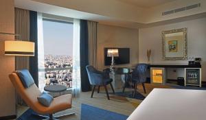 a living room with a table and chairs and a large window at Hilton Amman in Amman