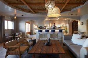 sala de estar con sofá y bar en Sea Breeze Santorini Beach Resort, Curio By Hilton en Perivolos