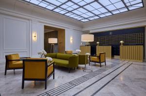 een lobby met een groene bank en stoelen bij Hotel Saski Krakow Curio Collection by Hilton in Krakau