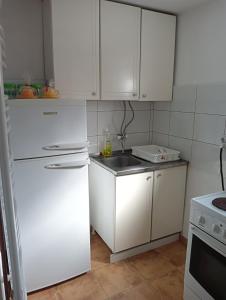 La cuisine est équipée de placards blancs et d'un réfrigérateur blanc. dans l'établissement Casa Orange, à Malo Središte