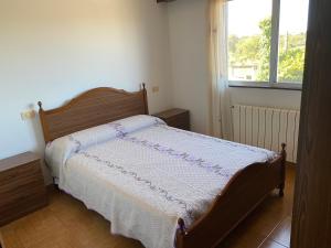 1 dormitorio con 1 cama con colcha blanca y ventana en Casa Portomeiro en San Román
