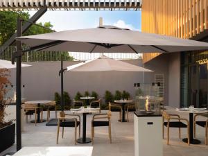 a patio with tables and chairs under an umbrella at Hilton Garden Inn Evora in Évora