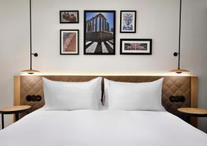 a bedroom with a white bed with four pictures on the wall at Hilton Garden Inn Evora in Évora