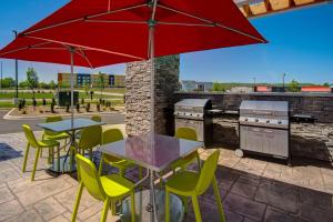 un patio con mesas, sillas y una sombrilla roja en Home2 Suites By Hilton Shepherdsville Louisville South, en Shepherdsville