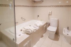 a white bathroom with a tub and a toilet at Wyndham Garden Santiago Kennedy in Santiago