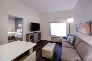 sala de estar con sofá, TV y cama en Hyatt House Colorado Springs Airport en Colorado Springs