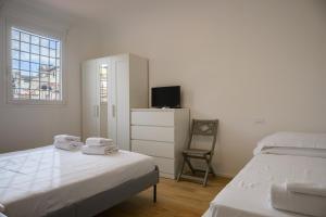 een witte slaapkamer met 2 bedden en een televisie bij Sapiti Modern by Mmega in Florence