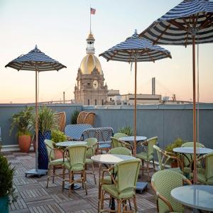 a patio with tables and chairs and umbrellas at The Drayton Hotel Savannah, Curio Collection by Hilton in Savannah