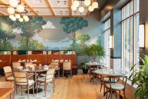 a restaurant with tables and chairs and a mural at The Drayton Hotel Savannah, Curio Collection by Hilton in Savannah +42 photos