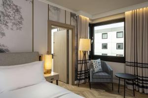 ein Schlafzimmer mit einem Bett, einem Stuhl und einem Fenster in der Unterkunft DoubleTree by Hilton Berlin Ku'damm in Berlin